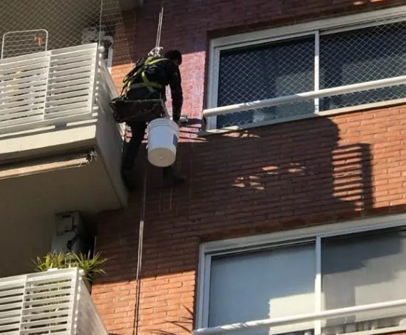 Operario de Alta Group realizando hidrolavado en fachada de edificio residencial