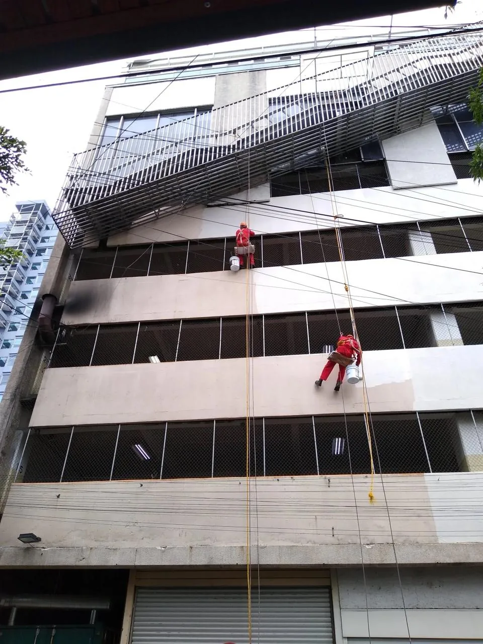 Operario de Alta Group realizando trabajos de pintura en altura sobre fachada