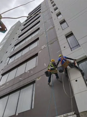 Fachada de edificio de ladrillo a la vista, con balcones e instalaciones de aire acondicionado, intervenida por Alta Group